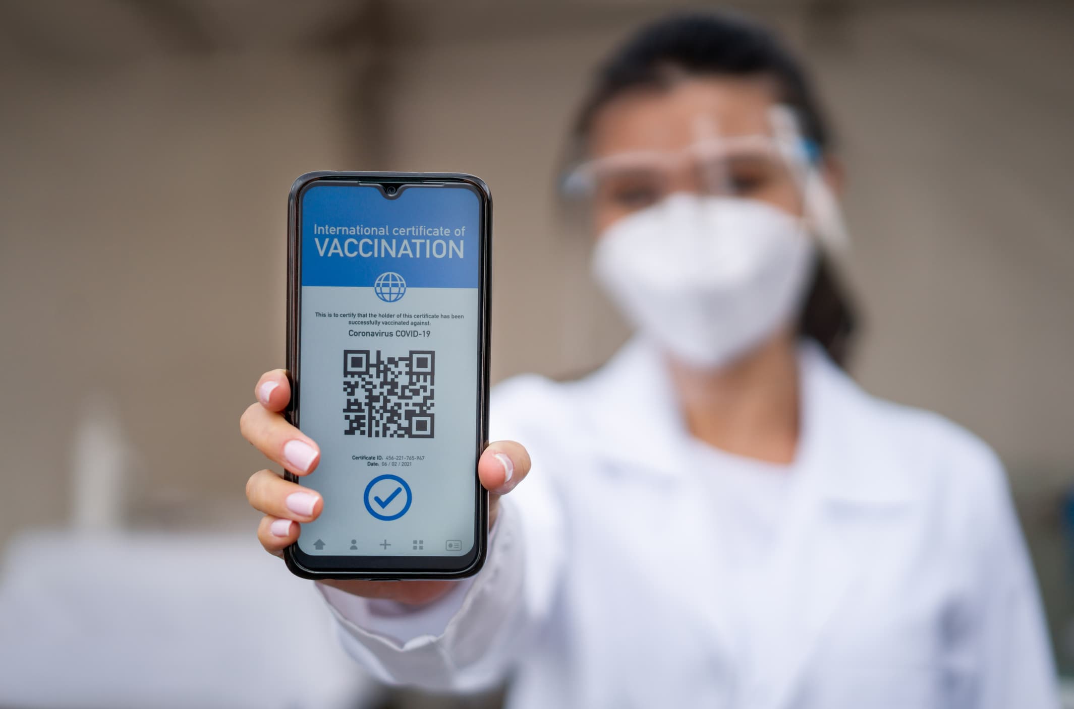 Healthcare worker holding a COVID-19 immunity passport on her cell phone