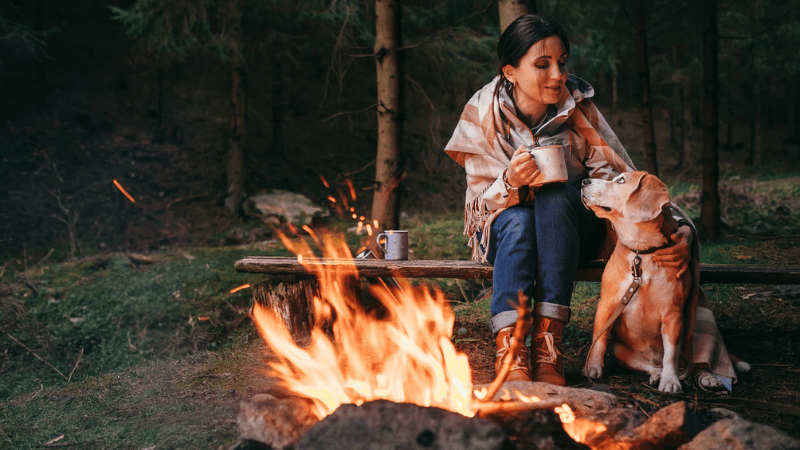 travel nurse camping with her dog at a bonfire